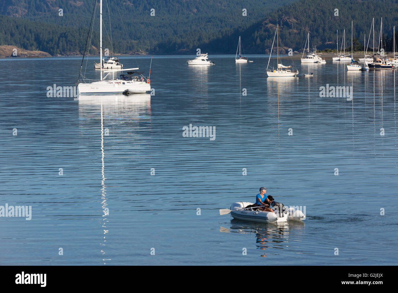 Eine Frau und ihr Hund Begleiter Reihe heraus, um ihr Boot vor Anker in Drew Hafen Quadra Island Discovery Islands British Columbia Kanada Stockfoto