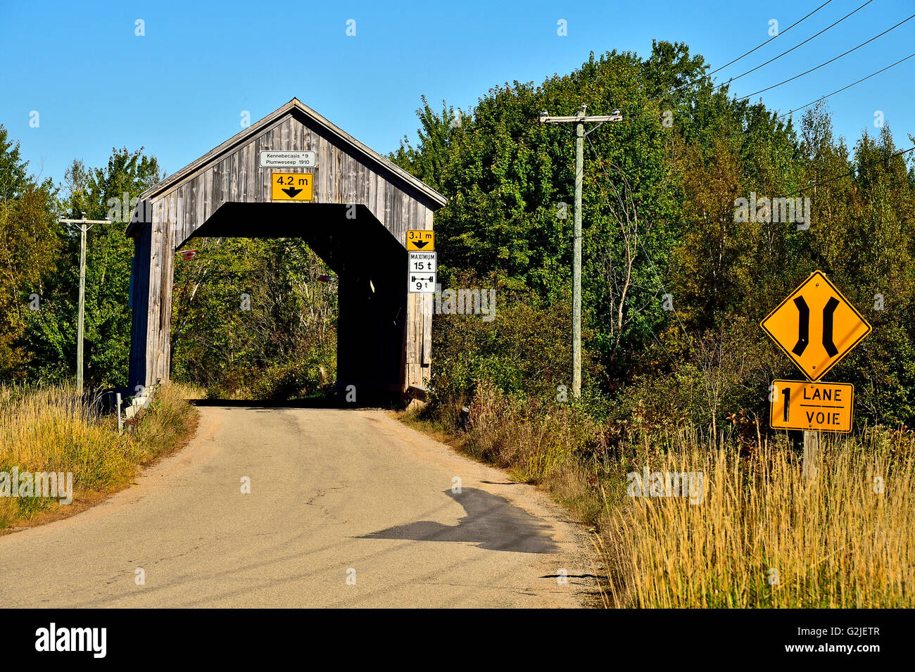 Eine hölzerne einspurige überdachte Brücke, erbaut 1910 überspannt einen Stream auf einer zweispurigen Straße Plumweseep im ländlichen New Brunswick, Kanada Stockfoto