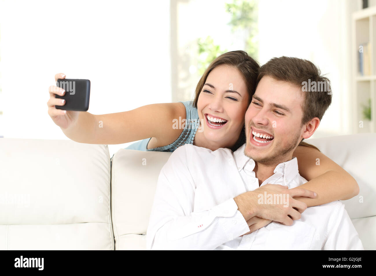 Ehe oder ein paar Lachen und dabei ein Selbstporträt mit Telefon sitzen auf einer Couch zu Hause Stockfoto