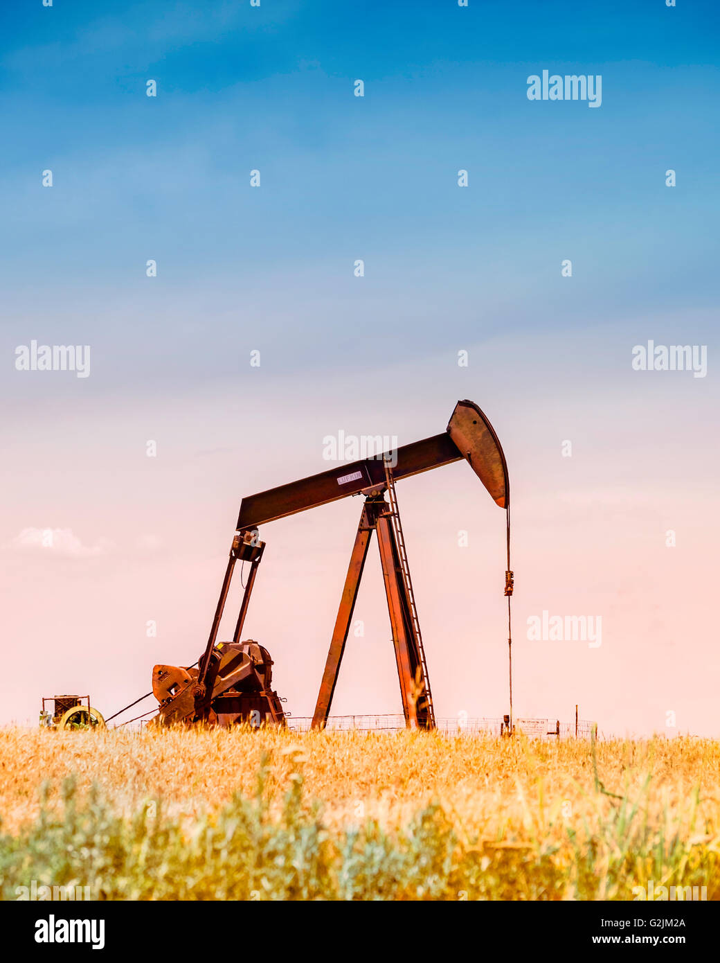 Ein Bohrschwengels Pumpen Öl in der Mitte ein Reifen Weizenfeld reif für die Ernte in Oklahoma, USA. Filter angewendet. Stockfoto