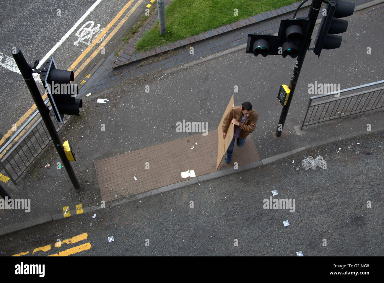 Junger Mann überquert Straße mit Paket von oben an der Ampel, Glasgow, Schottland, Großbritannien. Stockfoto