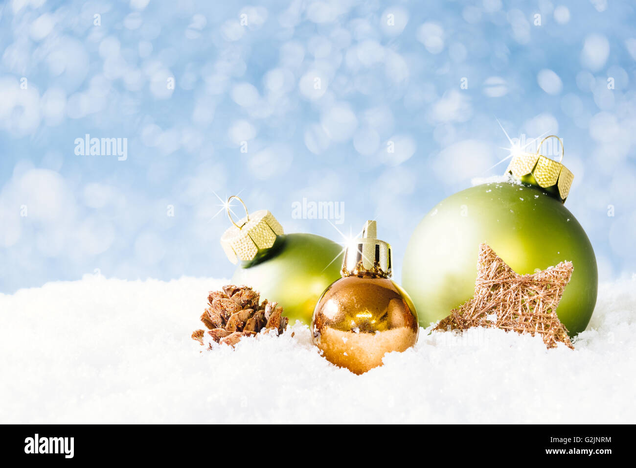 Ein Feuer-Kegel und drei Weihnachtskugeln auf Schnee mit weichen Bokeh blauen Hintergrund. Stockfoto