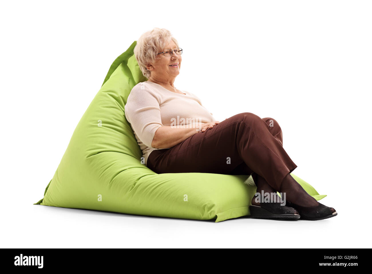 Entspannte senior Dame sitzt auf eine angenehm grüne Sitzsack isoliert auf weißem Hintergrund Stockfoto