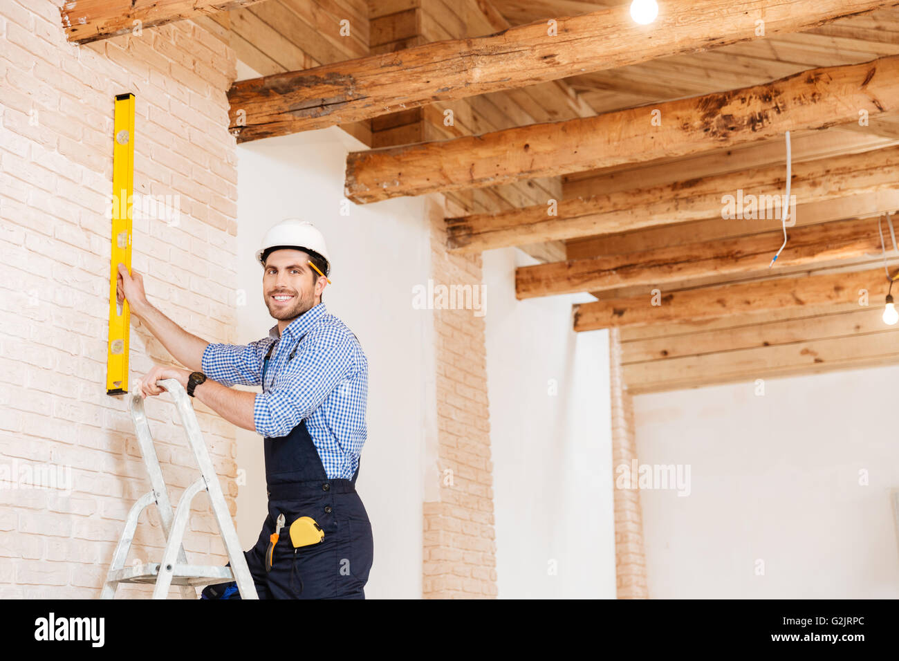 Smilling schön Builder-Tonwert und stehen in der Ladder an den Arbeitsbereich drinnen Stockfoto