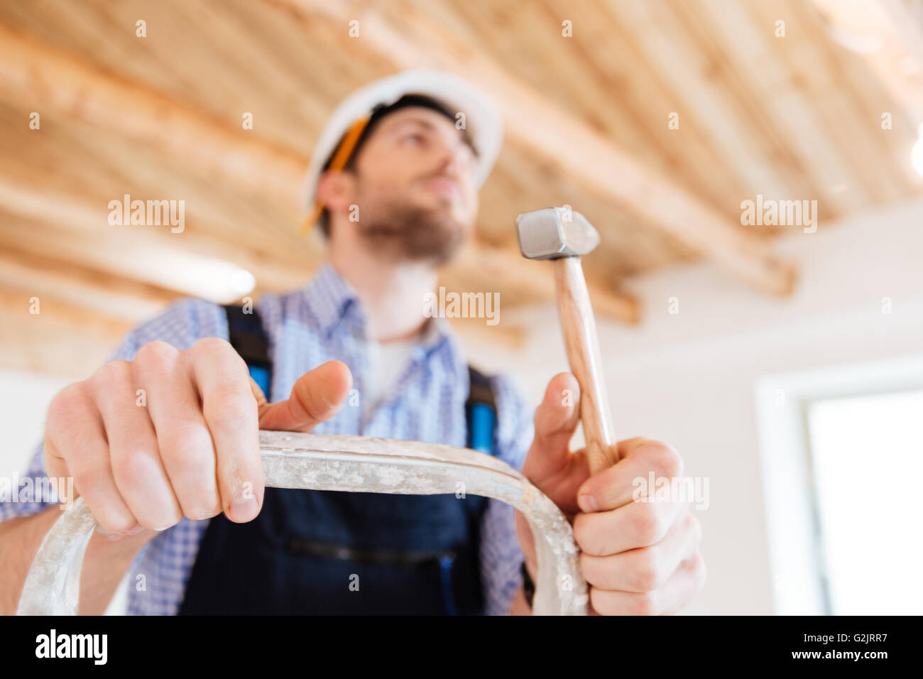 Close-up Portrait von ein Handwerker mit einem Hammer in der Hand, steht auf der Leiter, unkonzentriert Stockfoto