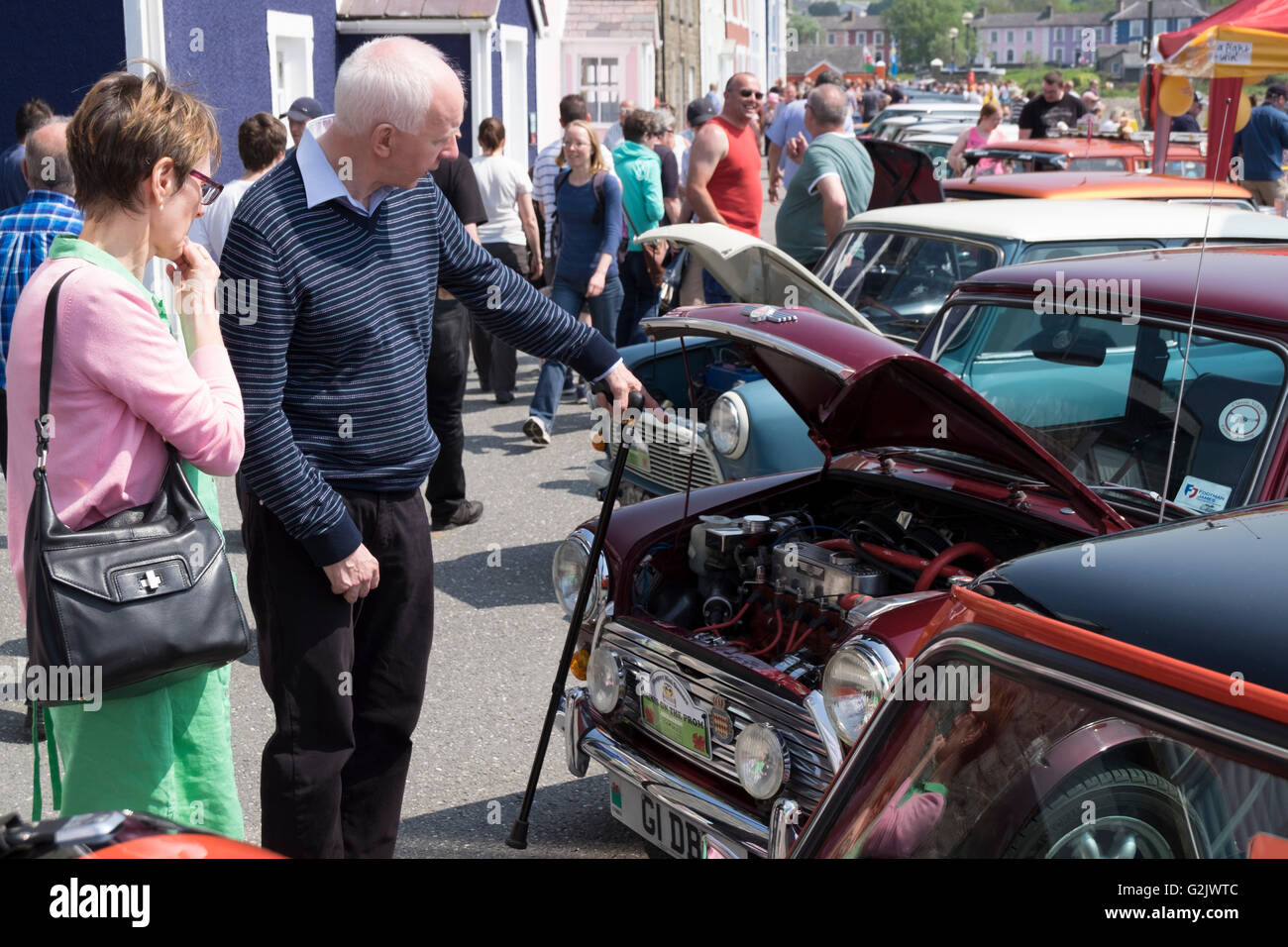 Ein Mann auf den Motor ein Austin Mini im Gespräch mit einer Frau auf eine geschäftige Quay Parade in Aberaeron, kann Bank Holiday Wochenende zeigen. Stockfoto