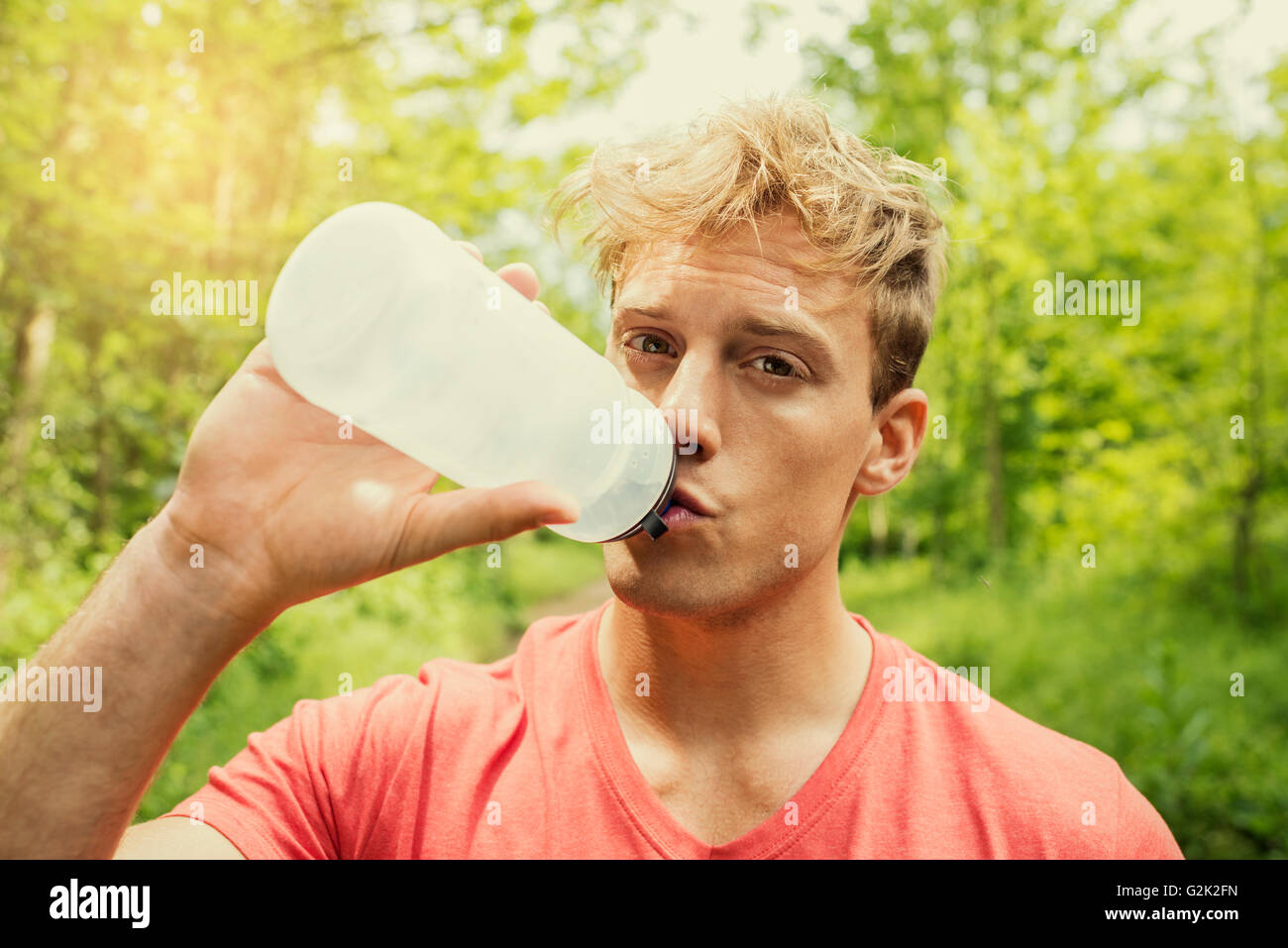 Athletische Sportler trinken Energy-Drink. Bäume-Wald Mann Fließwasser Stockfoto