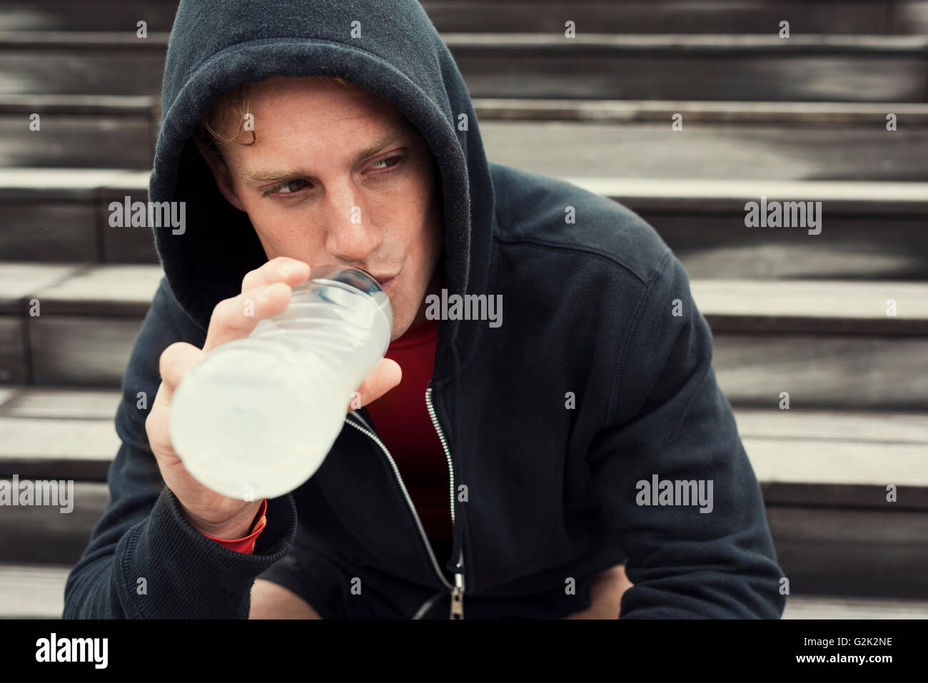 Urbanen Sportler ausruhen nach Training, sitzt auf der Treppe. Wasser zu trinken Stockfoto