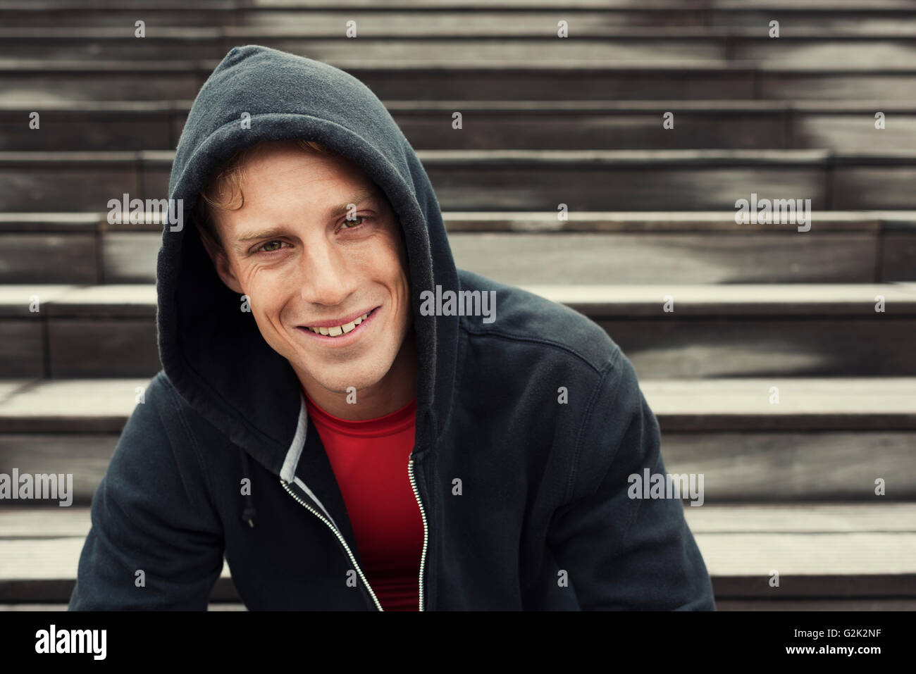 Porträt des jungen urbanen Sportler. Schwarzer Hoodie. Sitzt auf der Treppe Stockfoto
