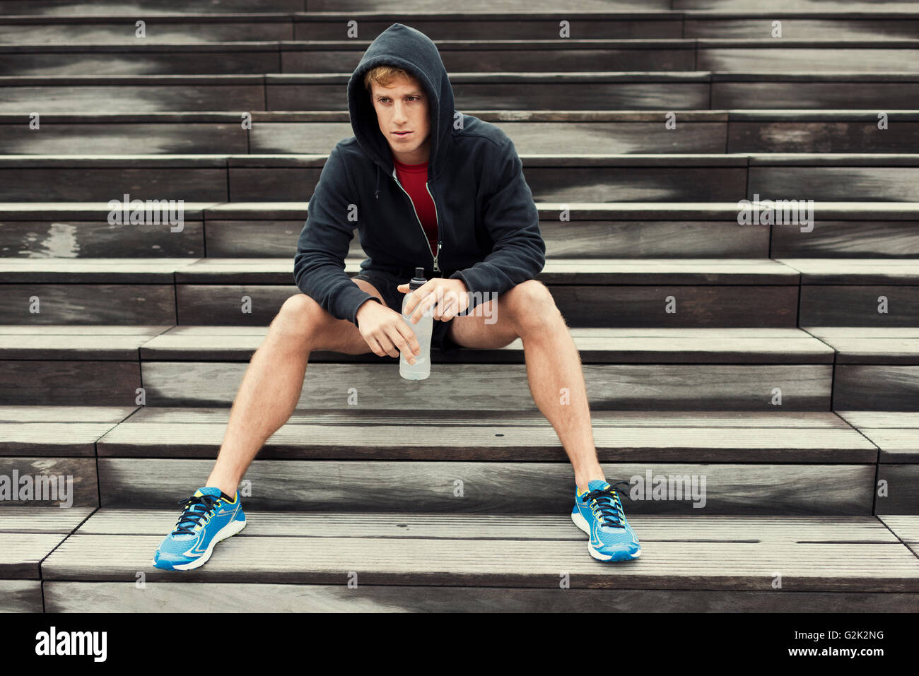 Urbanen Sportler ausruhen nach Training, sitzt auf der Treppe. Wasser zu trinken Stockfoto