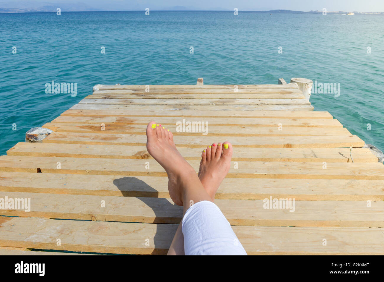 Womans Beine auf einem Dock beim Entspannen am Meer Stockfoto