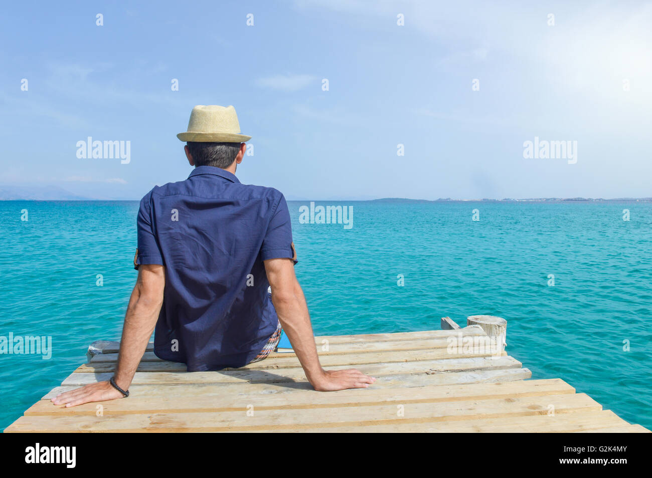 Mann sitzt auf einem Dock am Meer Stockfoto