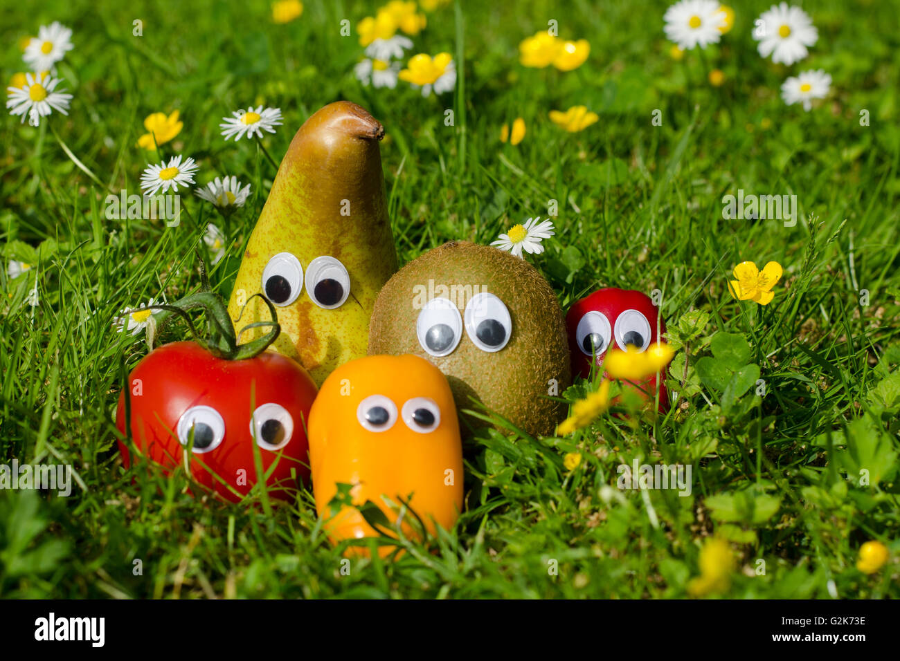 Lustiges Gemüse und Obst mit Augen in einer Sommerwiese Stockfoto
