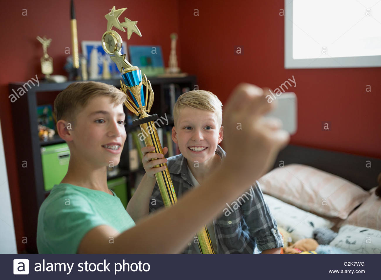 Verspielte Jungs mit Trophäe unter Selfie im Schlafzimmer Stockfoto