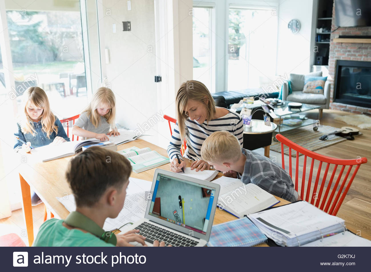 Mutter hilft Sohn Hausaufgaben am Esstisch Stockfoto