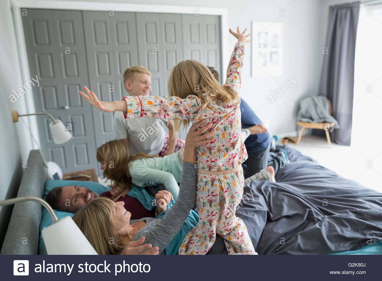 Verspielte Kinder im Schlafanzug auf die Eltern im Bett springen Stockfoto