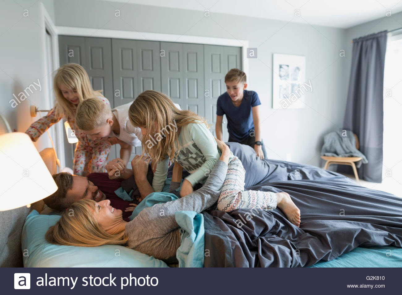 Verspielte Kinder im Schlafanzug, die Bekämpfung der Eltern im Bett Stockfoto