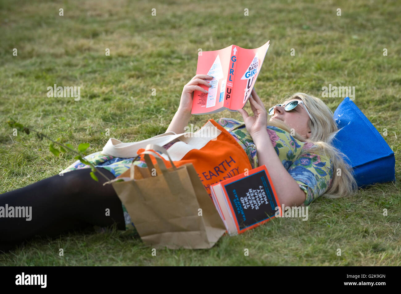 Junge Frau entspannen & Lesen eines Buches auf dem Rasen im Hay Festival 2016 Stockfoto