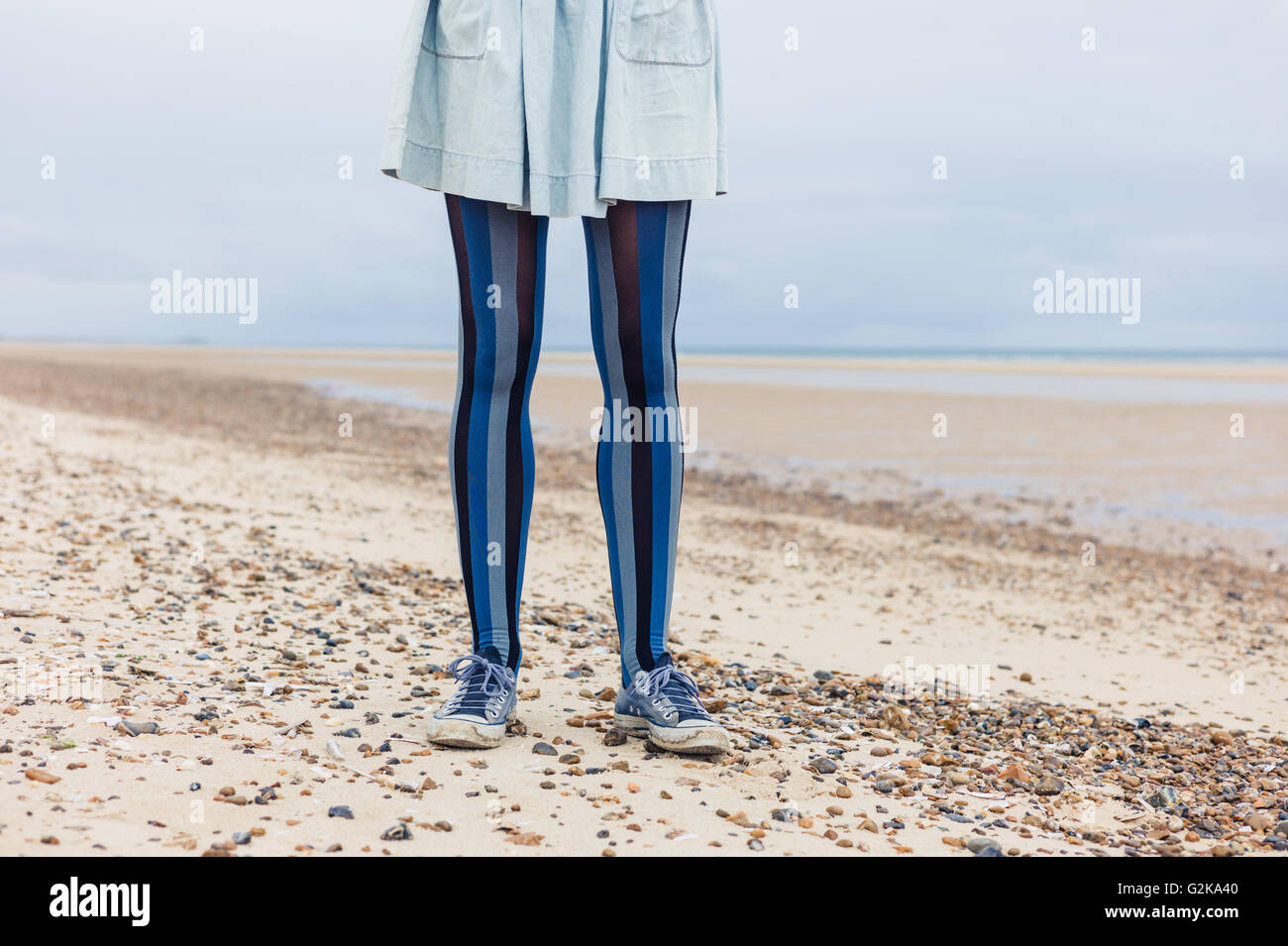 Die Beine einer jungen Frau wie sie am Strand steht Stockfoto