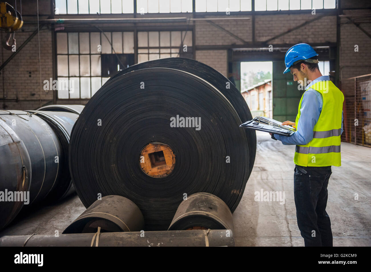 Arbeitnehmer mit Dokumenten in Fabrikhalle mit Rollen aus Kautschuk Stockfoto