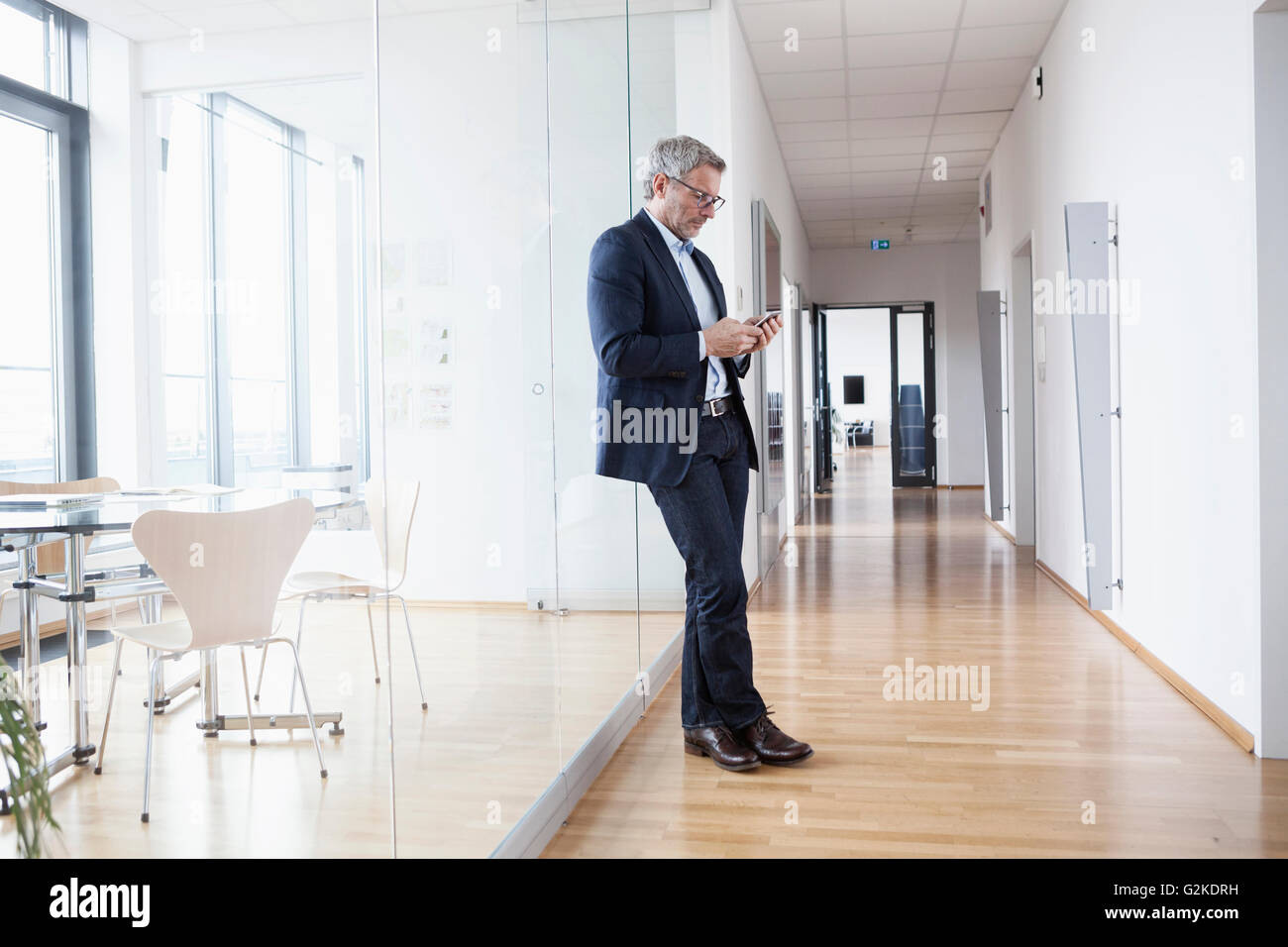 Erfolgreicher Geschäftsmann mit in sein Büro Lookking am Smartphone Stockfoto