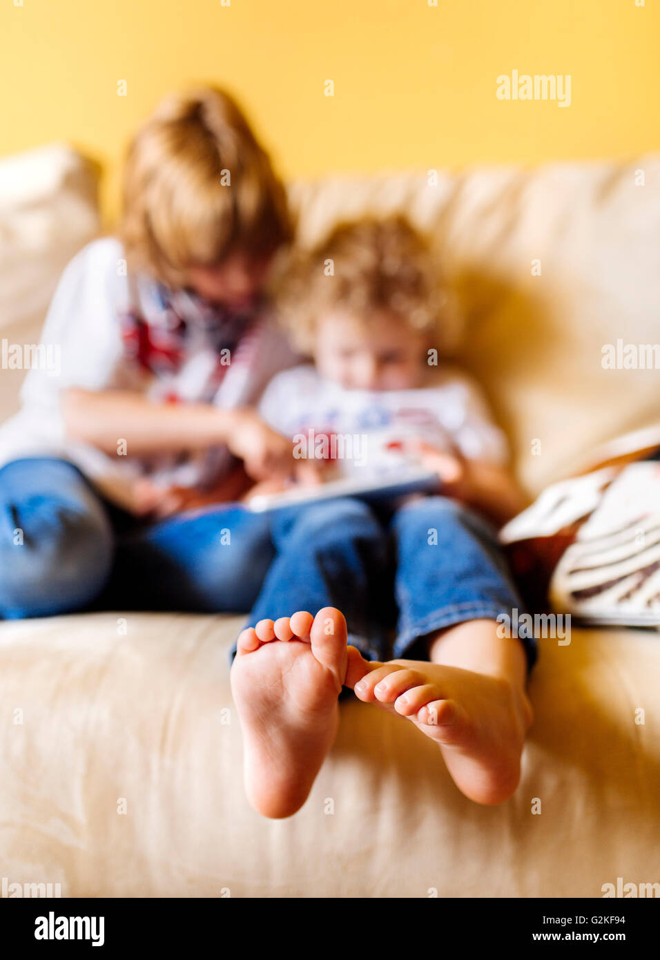 Füße des kleinen Jungen sitzen auf der Couch mit seinem Bruder, Nahaufnahme Stockfoto