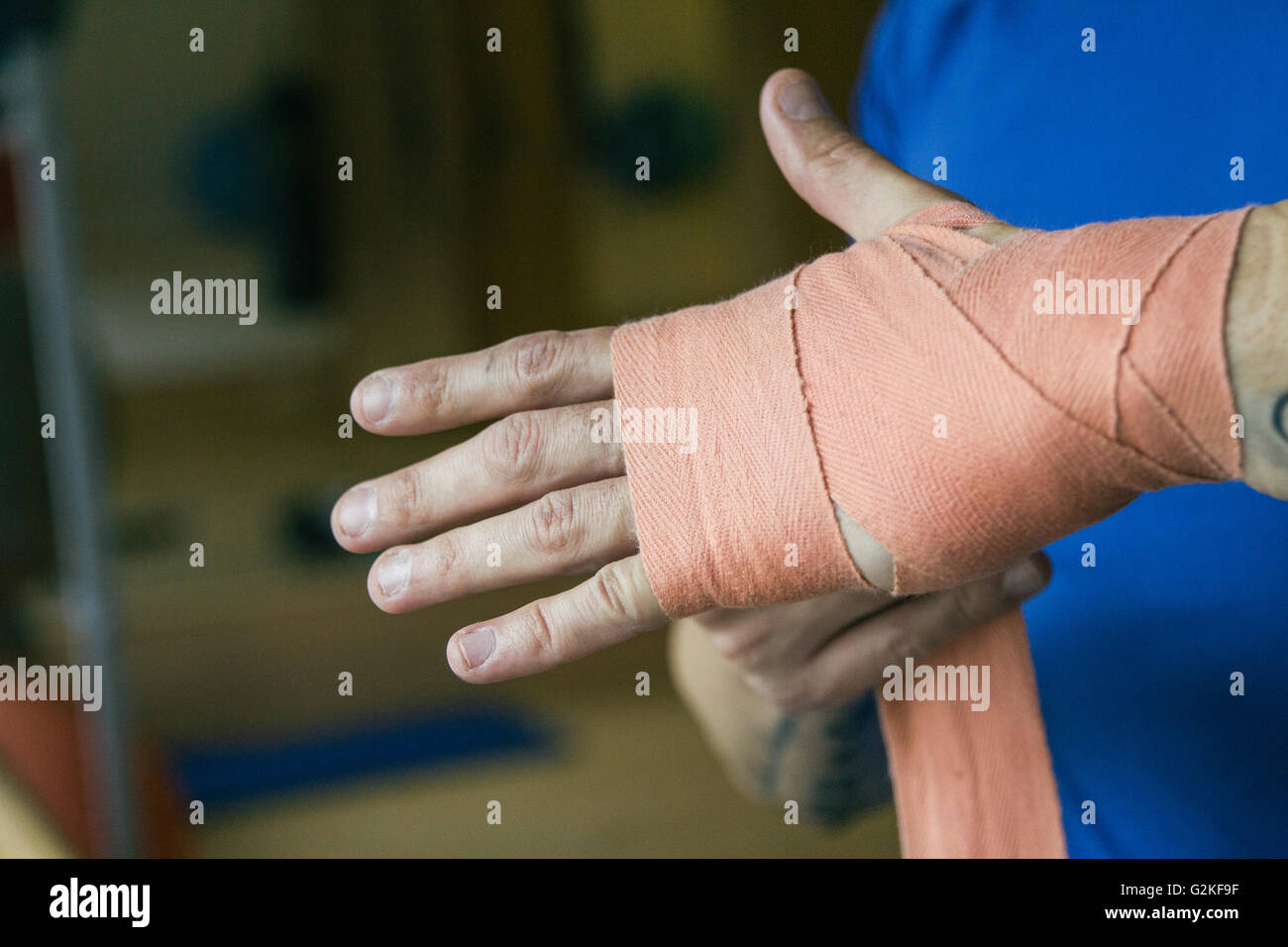 Mann, der auf einen Verband an der Hand vor einem Boxtraining Stockfoto