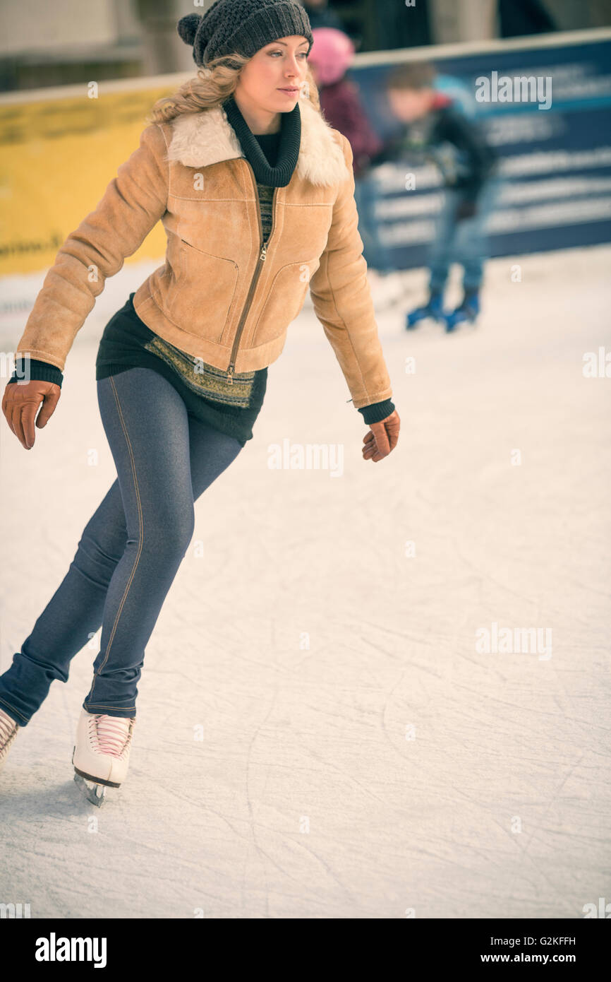 Junge Frau, die auf Outdoor-Eisbahn Schlittschuh laufen Stockfoto