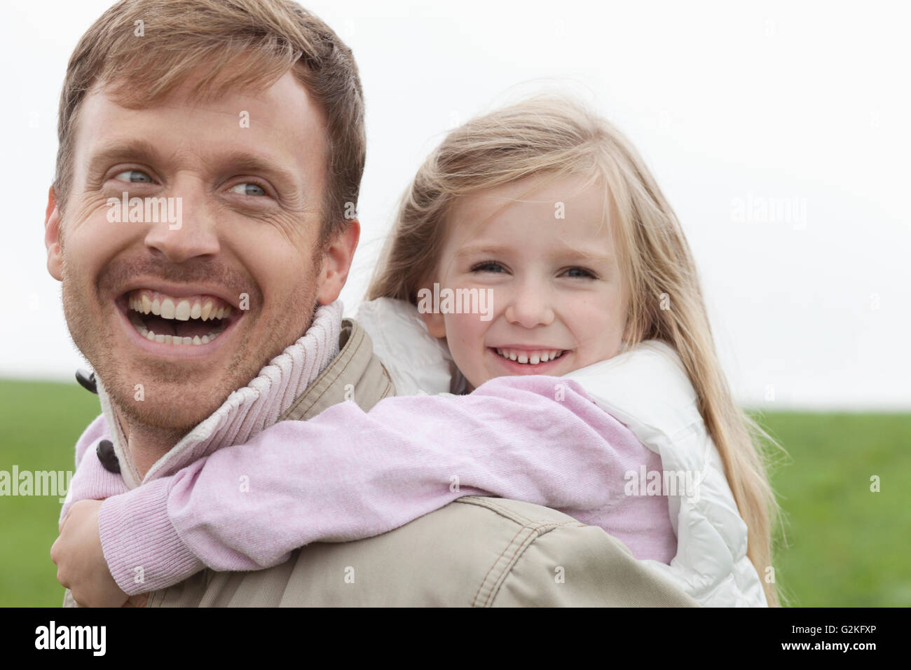 Glücklicher Vater mit Tochter Huckepack im freien Stockfoto