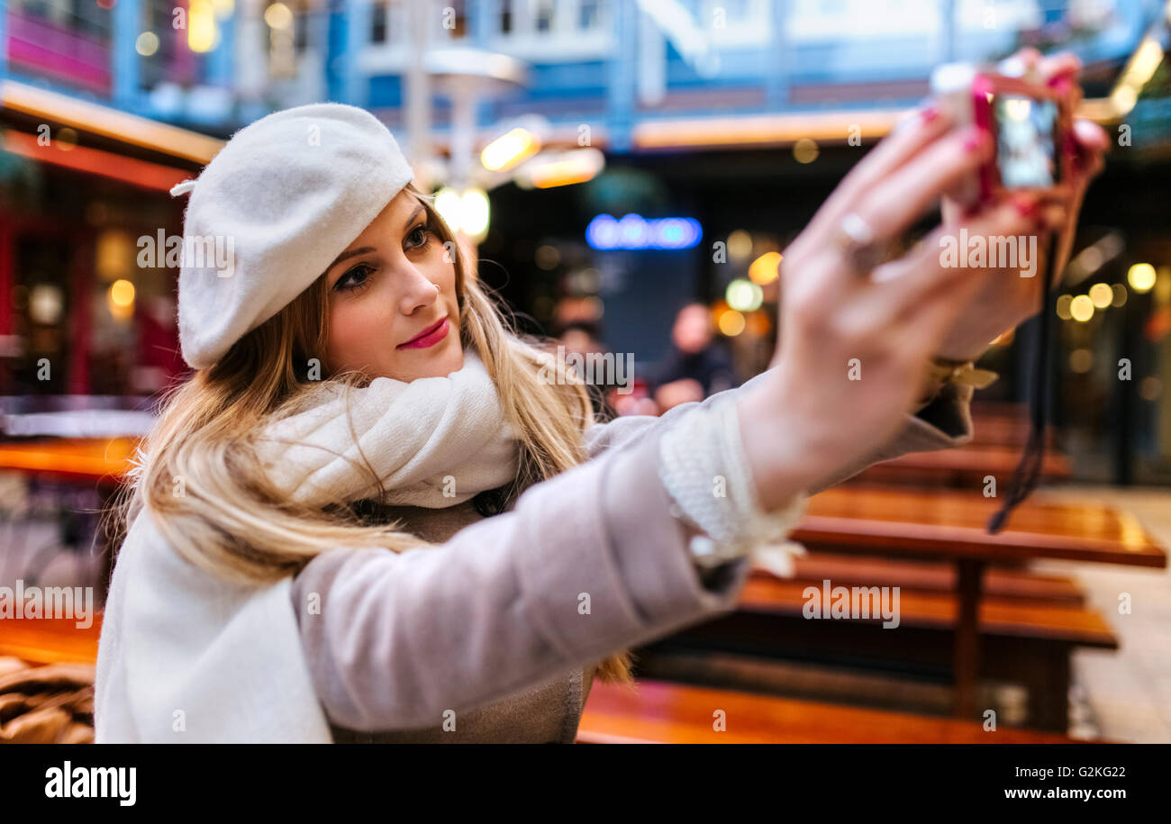 Junge Frau trägt Mütze nehmen Selfie mit Digitalkamera Stockfoto