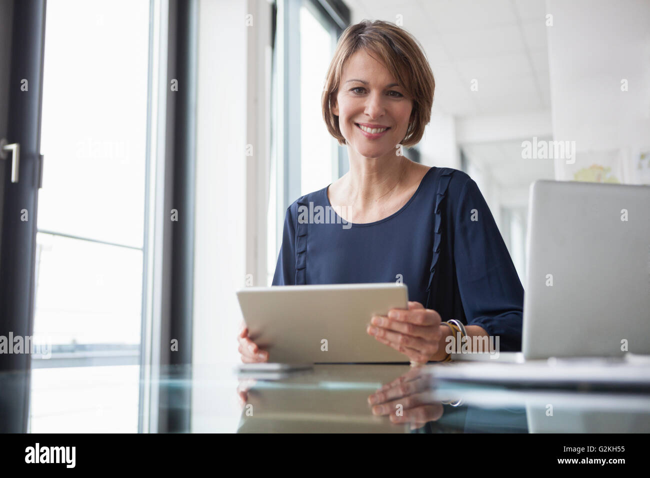 Porträt von lächelnden Geschäftsfrau mit digital-Tablette am Schreibtisch Stockfoto