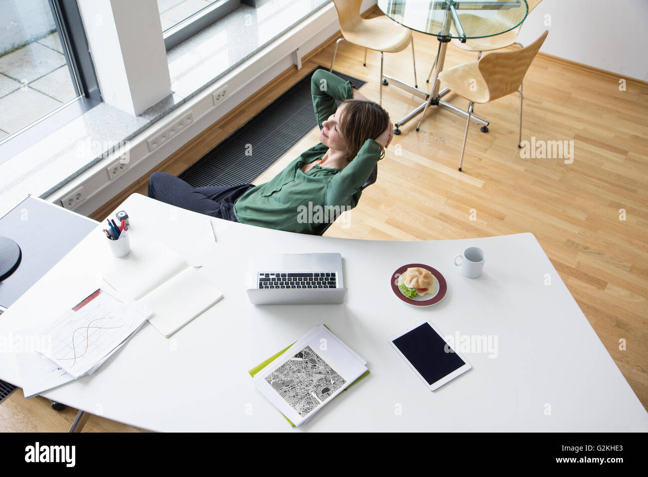Lächelnd Geschäftsfrau im Büro Schreibtisch lehnt sich zurück Stockfoto