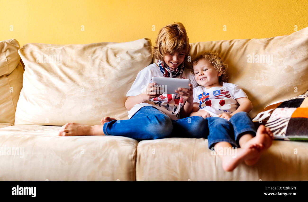 Zwei lächelnden jungen sitzen auf Couch mit digital-Tablette Stockfoto