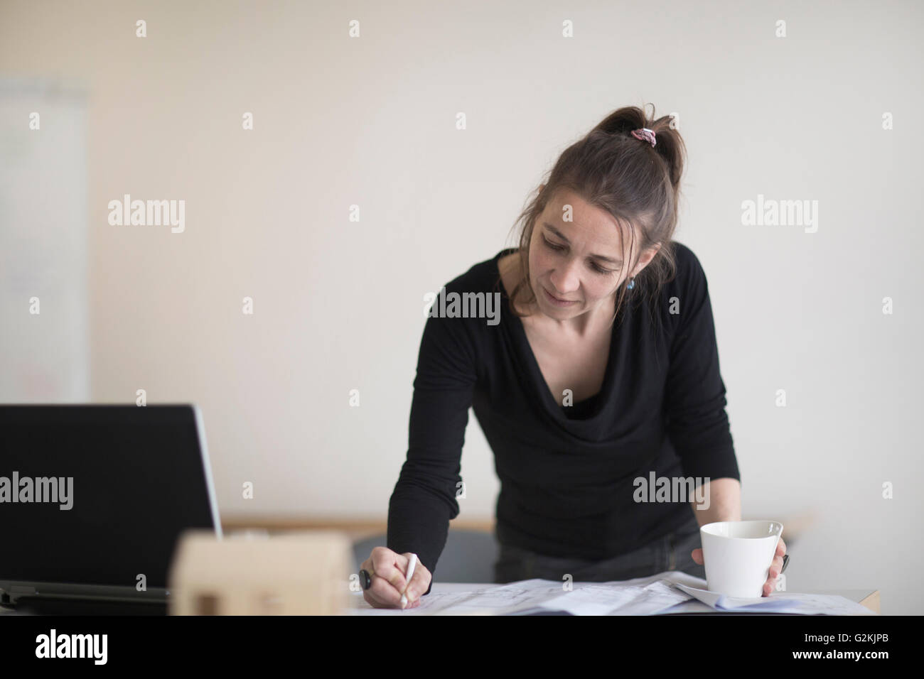 Frau im Büro arbeitet an Plan am Schreibtisch Stockfoto