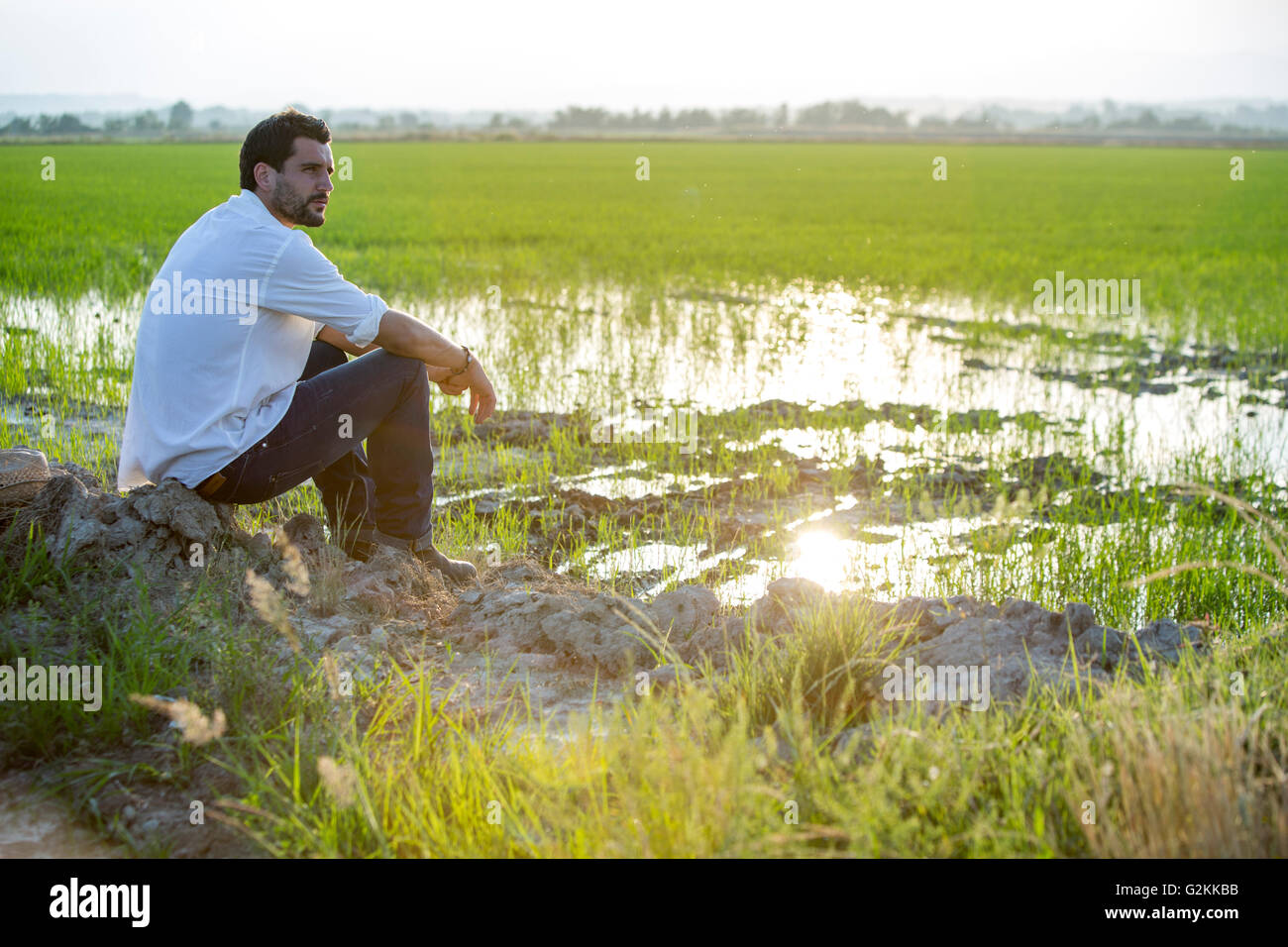 Junger Mann sitzt am Rand eines Feldes Stockfoto