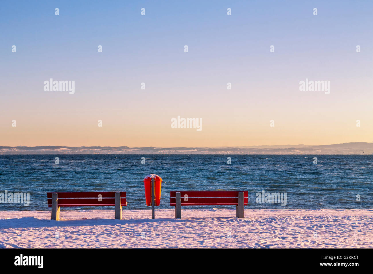 Schweiz, Arbon, zwei roten Sofas und einem Abfallbehälter vor dem Bodensee in der Dämmerung Stockfoto