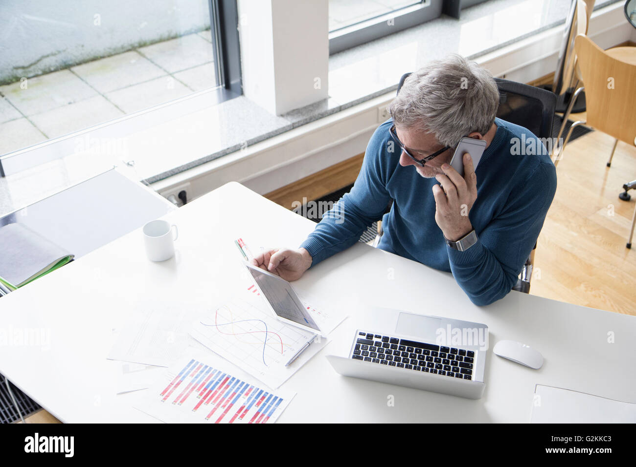 Reifer Mann im Büro mit Smartphone und Tablet-digitale arbeiten Stockfoto