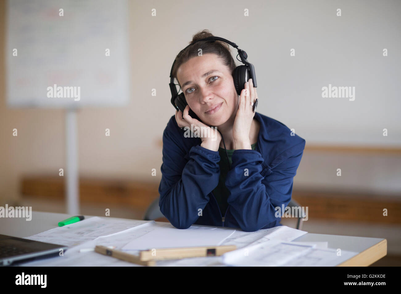 Frau mit Kopfhörern am Schreibtisch Stockfoto