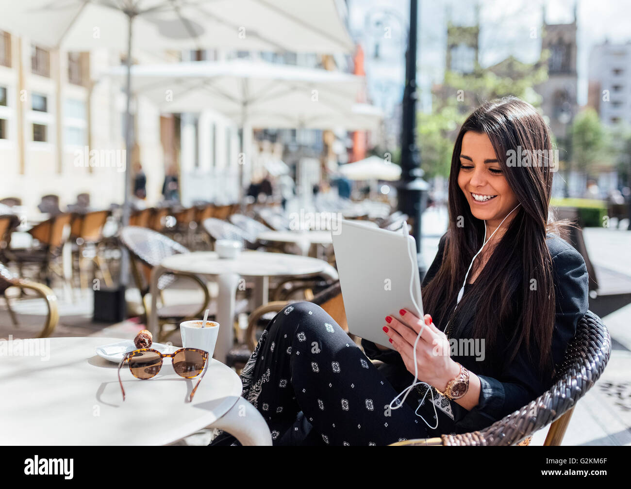 Hübsche junge Frau mit Kaffee, digital-Tablette, hören Musik, Straßencafé Stockfoto