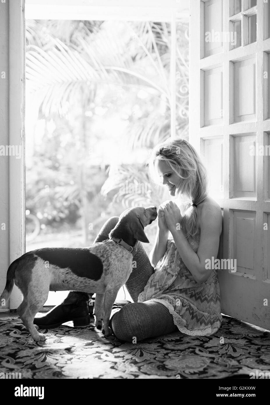 Junge Frau und Hund sitzt vor der offenen Tür Stockfoto