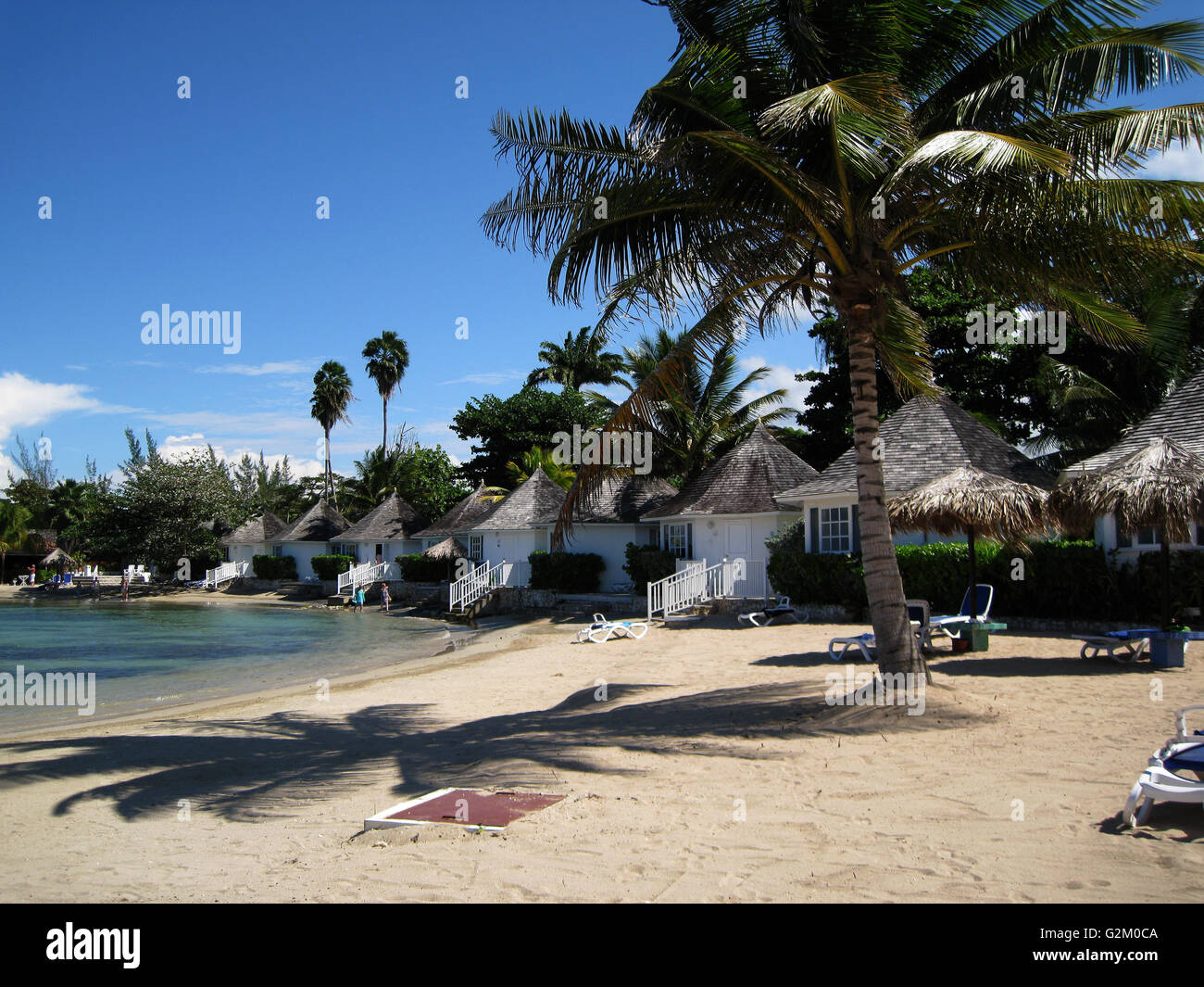 Schöne Sonne beleuchtet warmen karibischen Strand, goldenen Sand und dramatische Himmel, Decameron Hotel, Runaway Bay, mit Kokospalmen Stockfoto