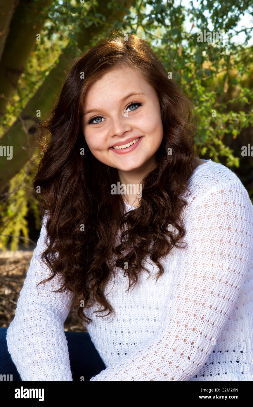 Ein schönes junges Mädchen mit großen, blauen Augen, Grübchen und braunen Haaren posiert für ein Porträt. Stockfoto