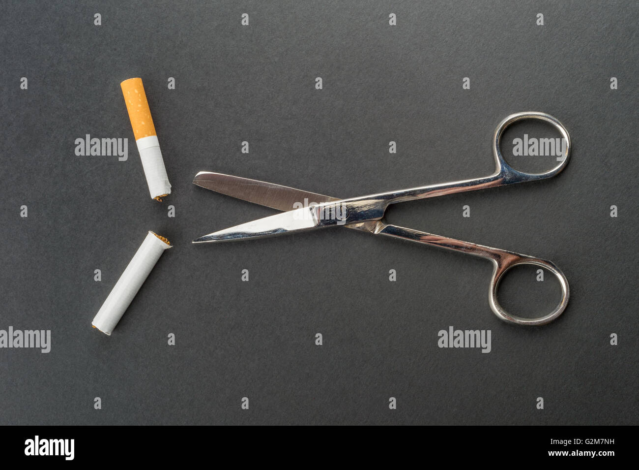 Aufhören zu rauchen - Schere schneidet eine Zigarette in einem dunklen grauen Hintergrund Stockfoto