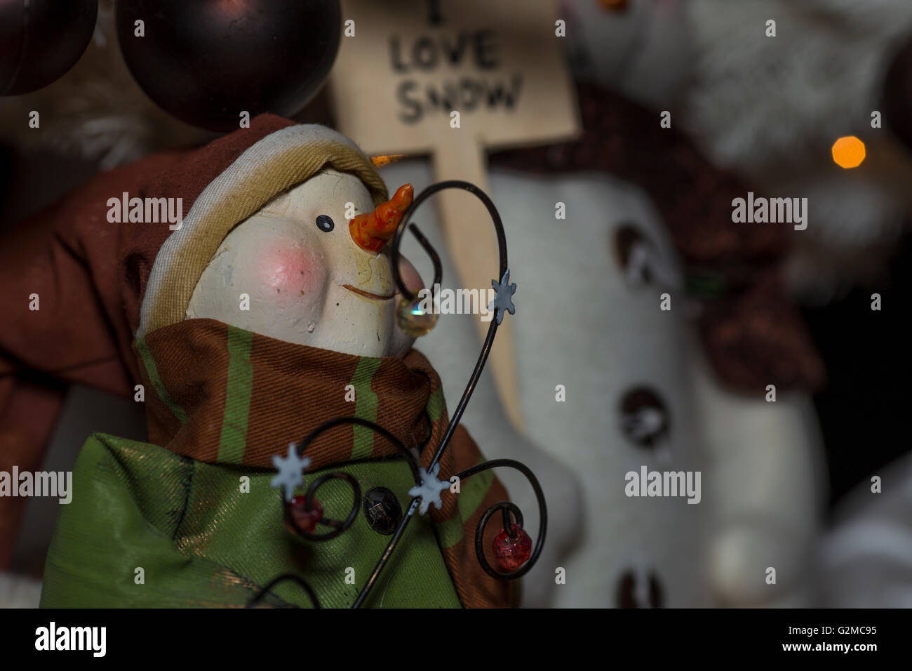 Christmas Ornament eines Schneemannes tragen einen Urlaub-Hut, einen Mantel und Schal und ein Schild im Hintergrund, das liest ich liebe Schnee. Stockfoto