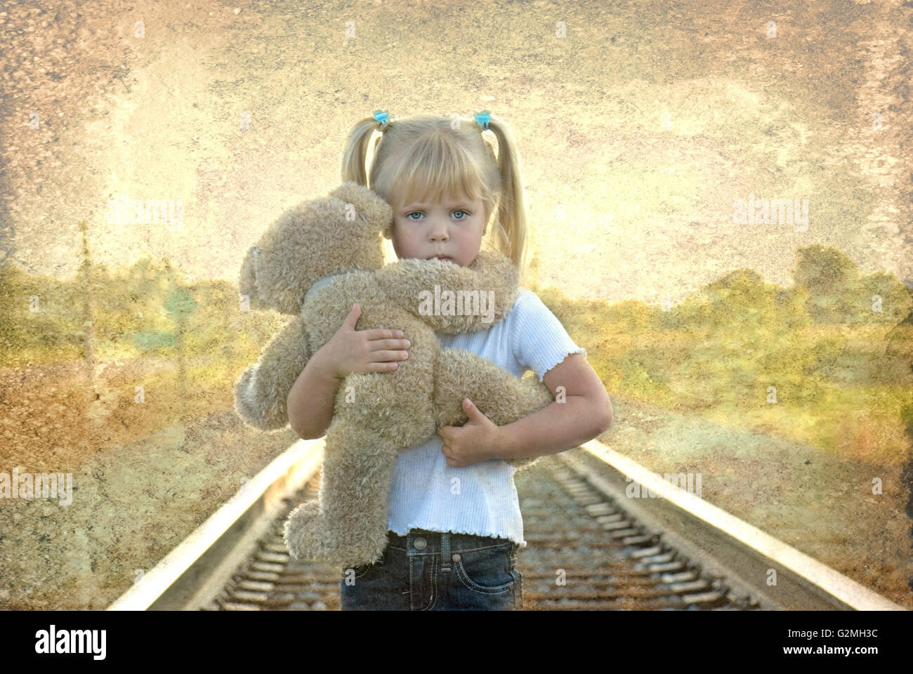 Trauriges Mädchen auf Eisenbahn verfolgt, hält einen Teddybär. Grunge Texturen Overlay hinzugefügt. Stockfoto