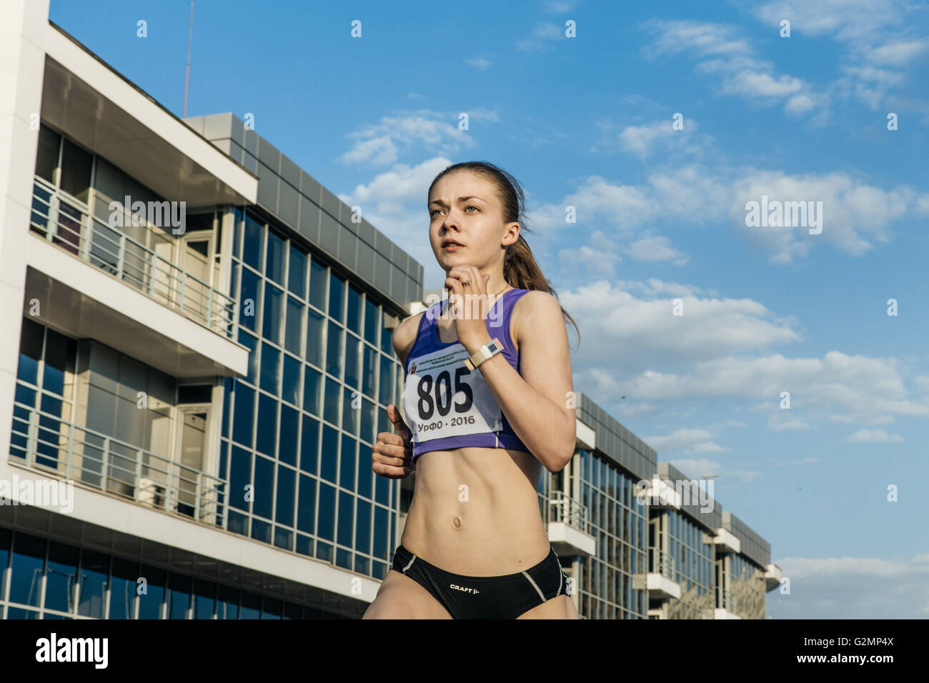 Mädchen-Läufer läuft im Stadion Hintergrund des blauen Himmels während UrFO Meisterschaft in der Leichtathletik Stockfoto