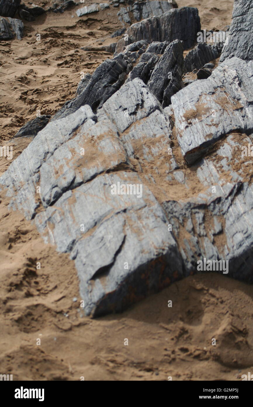 Teil eines großen Schiefer Felsens in den Sand am Strand Stockfoto