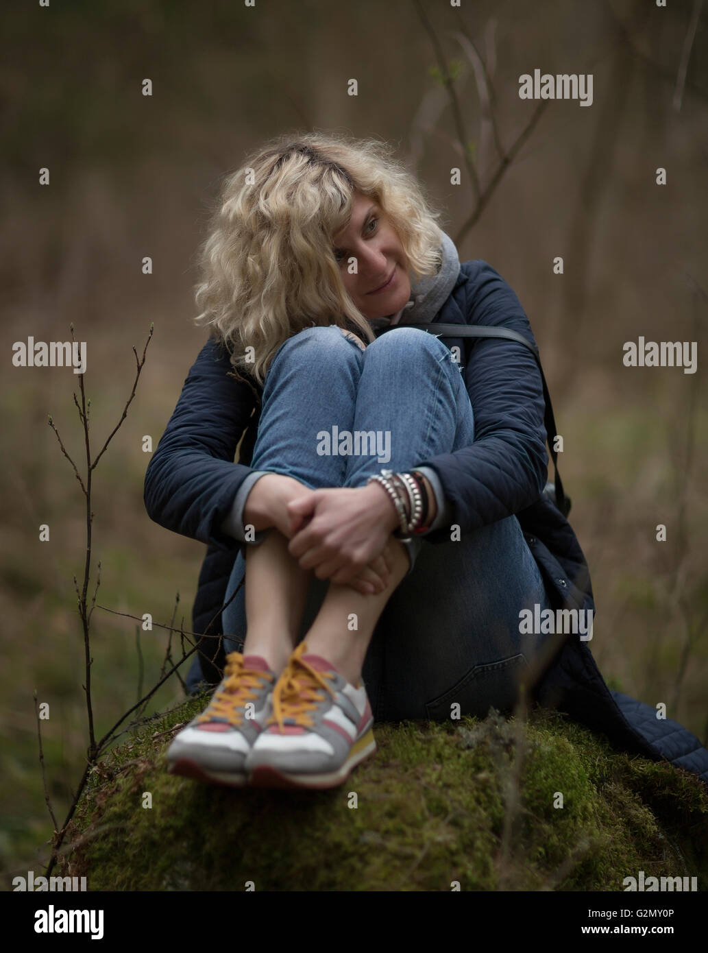 Blondes Mädchen ist auf dem Baumstumpf im Wald das gleiche wie Bild "Aljenuschka" von Wasnezow Sitzplätze Stockfoto