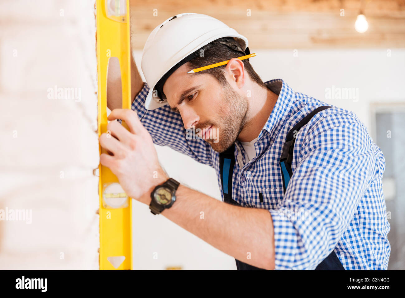Nahaufnahme eines nachdenklich Arbeitnehmers überprüfen die gelbe Ebene auf die Betonwand im Innenbereich Stockfoto