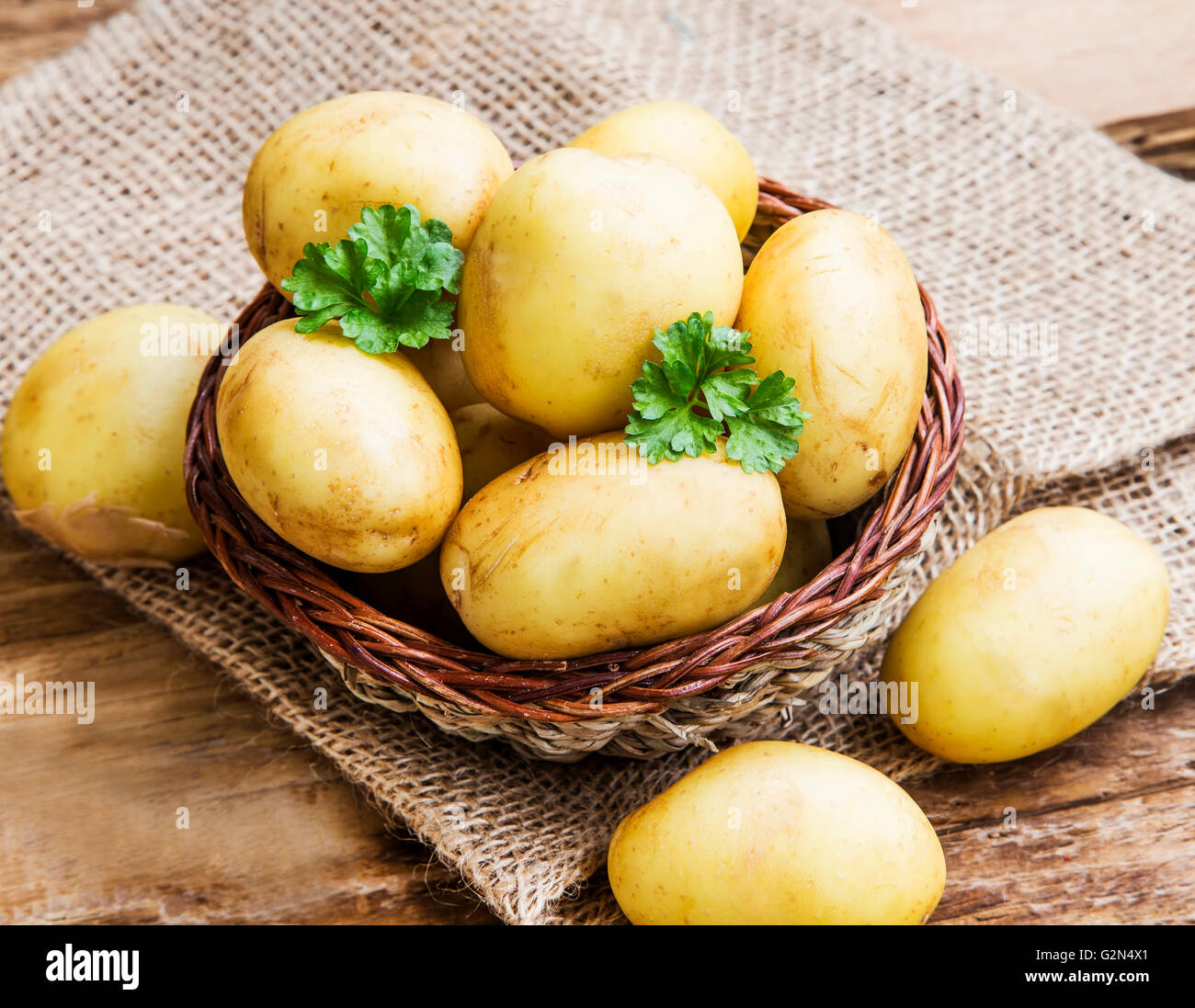 Junge Kartoffeln in einem Korb mit grüner Petersilie Blätter Stockfoto